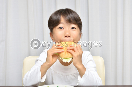 ハンバーガーを美味しそうに食べる女の子 ストックフォトの定額制ペイレスイメージズ