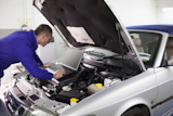 Mechanic typing on a PC next to a car